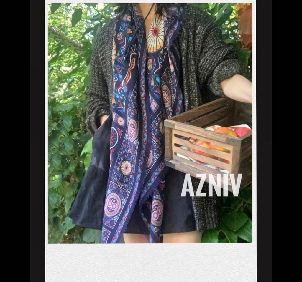 A shawl with wool and silk. Beautiful to wrap yourself. The color is navy blue, with a touches of golden yellow oranges, reds and light blue. A sundial with different shapes. 
