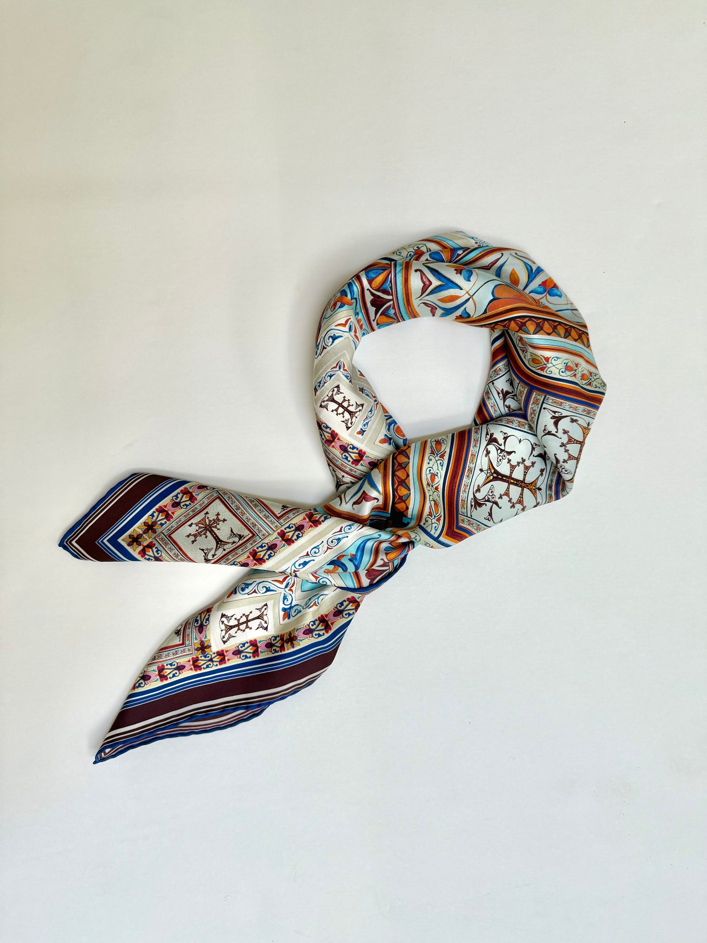 100 percent silk twill hand drawn. made in Como, Italy. Hand sewn. donate to Alzheimer's research and support. End Alzheimer's Disease. A story of long ago produced to reflect the modern adventurous women. Geometric figures, mosaic tiles with hints of baby blue, deep burgundy like mulled wine, flecks of pink and orange perfect for everyday wardrobe. 
