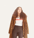 a girl with curly beach hair wearing a t-shirt with red writing that says lovely in Armenian and a leopard coat